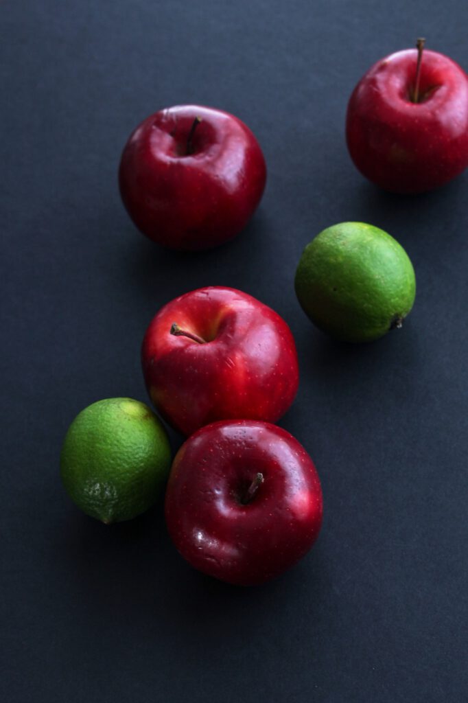 Manzanas rojas y limas sobre fondo oscuro