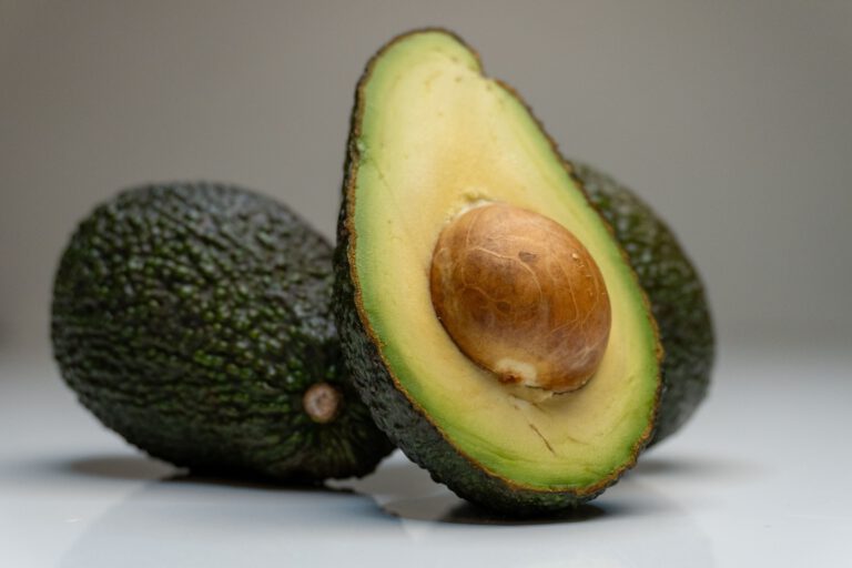 Palta cortada a la mitad junto a paltas enteras